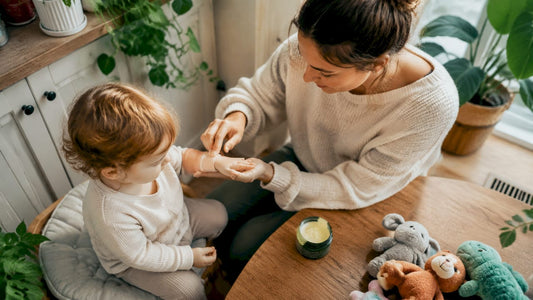 Mother applying moisturizer to toddler's hands