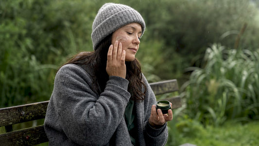 Woman applying tallow balm on cheek outdoors